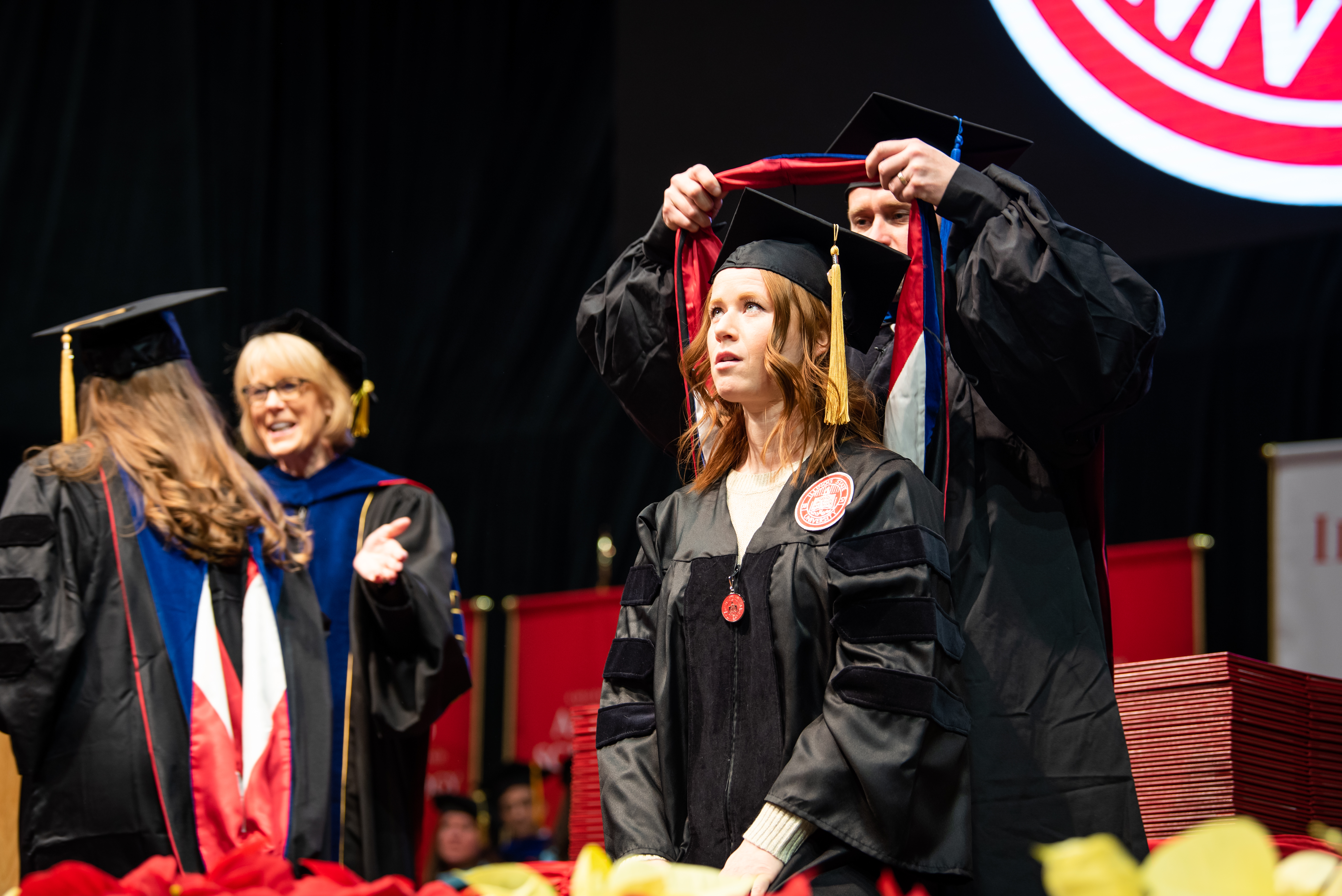 A doctoral student receiving their hood at graduation.